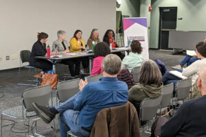 5 women seated behind a table in front of an audience